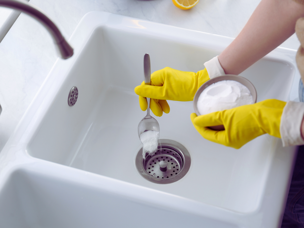 woman clearing clogged drain with baking soda