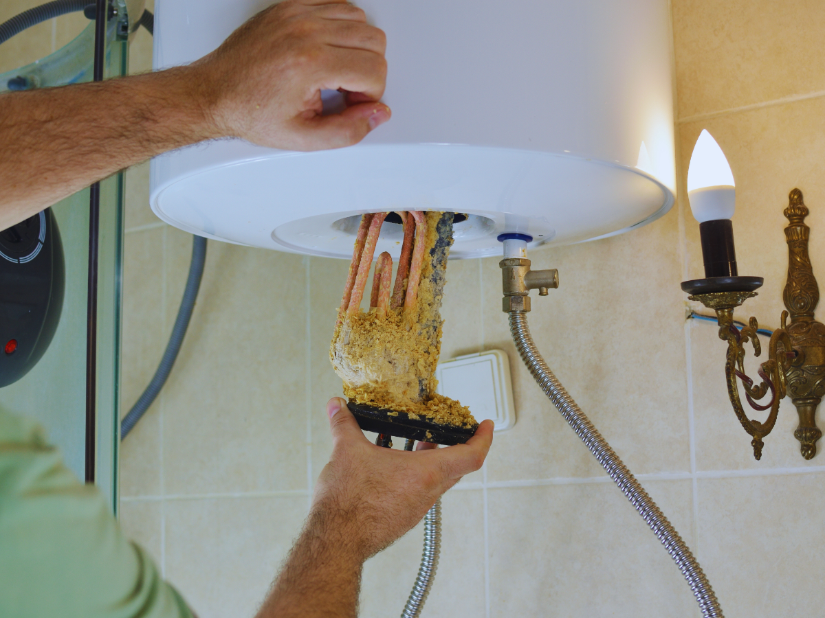 Plumber removing failing water heater element
